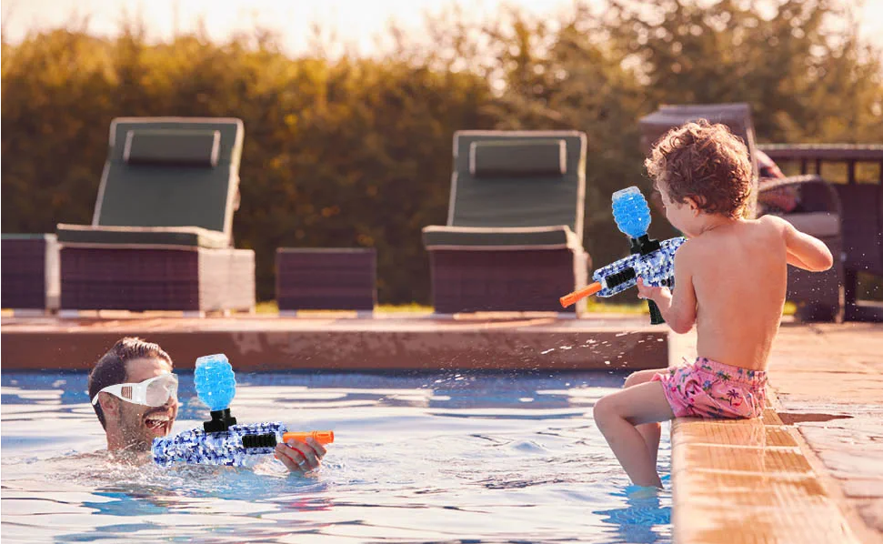Adults and children play with water guns by the pool.