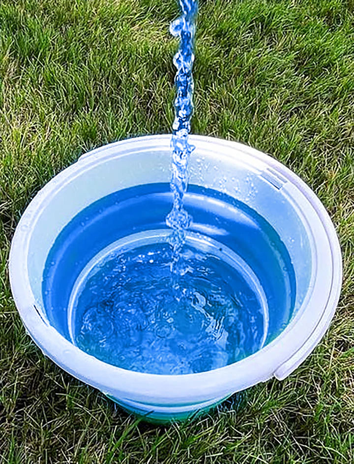 Partially fill the blue bucket on the grass with water.