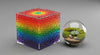 Colorful geometric cube and glass terrarium with plants on a gray background