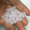 Hand holding a small pile of translucent white beads.