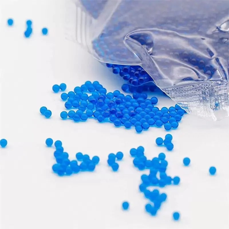 Blue beads spilling out of a clear plastic bag on a white background